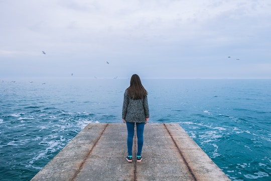 Image of a woman on a dock facing the ocean