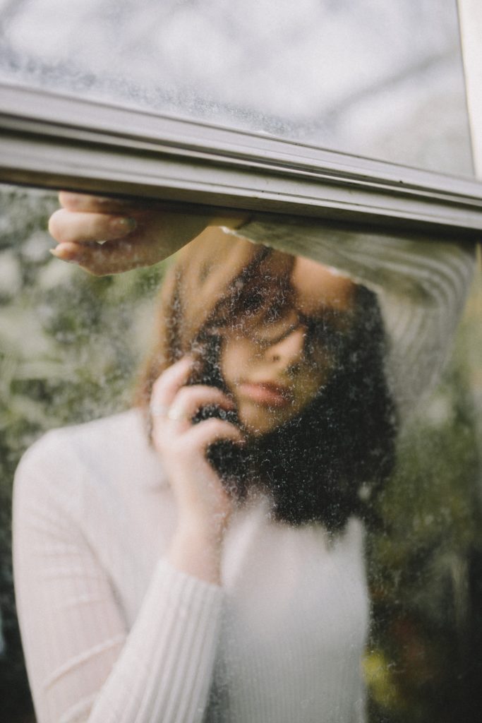 Woman looking through a Dirty Window