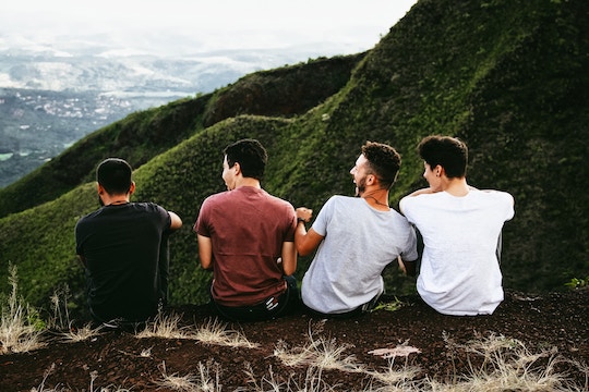 Image of four men sitting on the edge of a mountaintop