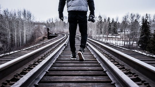 Image of a man walking down a railroad track