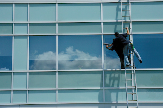 Image of man washing windows on a tall building