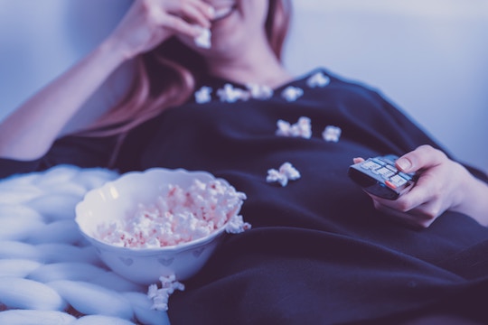 Image of a woman watching TV and eating popcorn