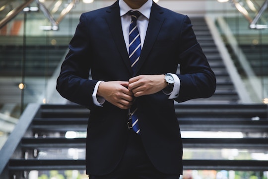 Image of a man buttoning his suit jacket