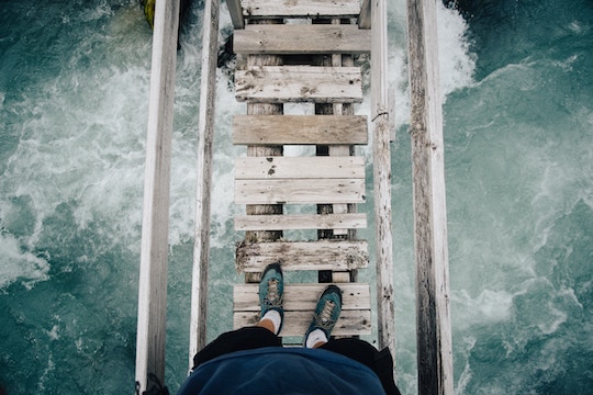 Image of a person standing on a rickety wood bridge over rapids