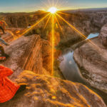 Image of a man on a mountain, taking a photo of the sunrise