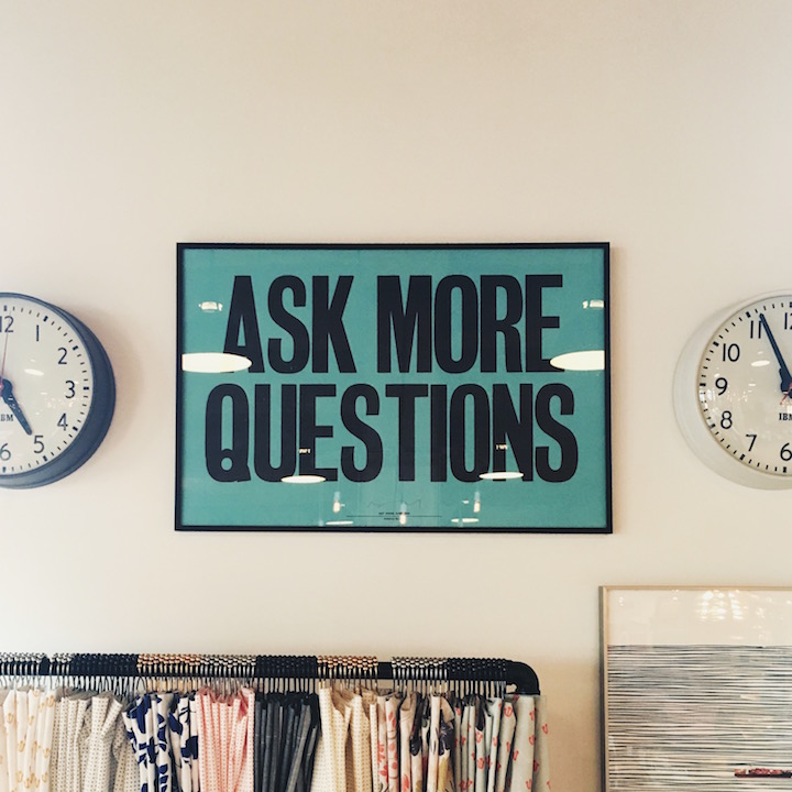 "ask more questions" sign between two clocks