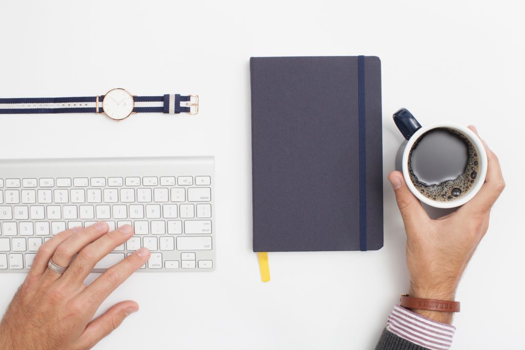 Image of keyboard, hands, coffee, and watch