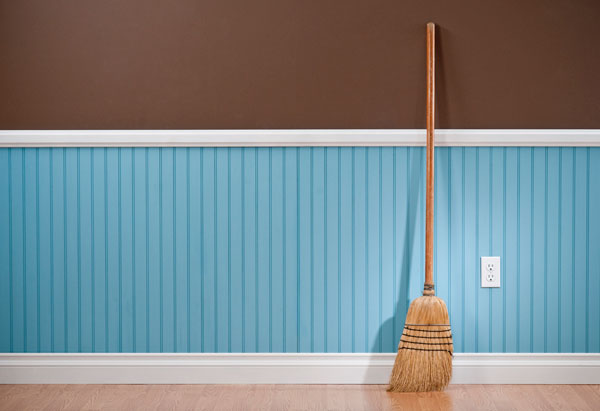 Image of a broom leaning against a blank wall