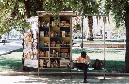 Image of a man reading at a bus stop