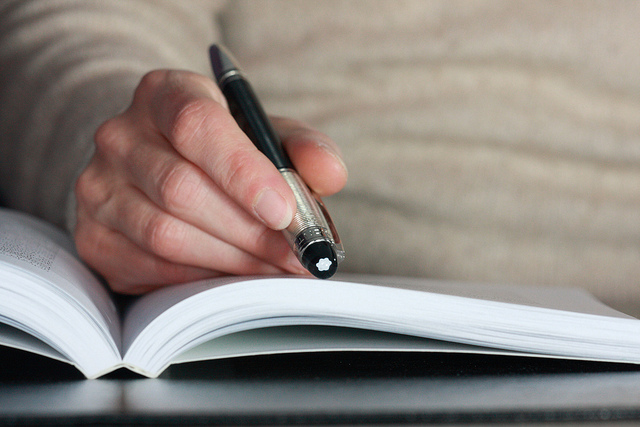 Image of a man following text with a pen in hand