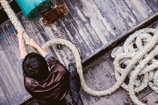 Image of a man tugging a thick rope