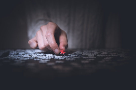 image of a hand placing a piece in a jigsaw puzzle