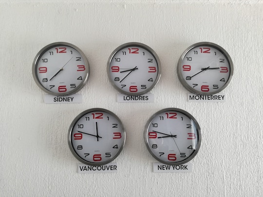 Image of five clock on a wall, showing different time zones