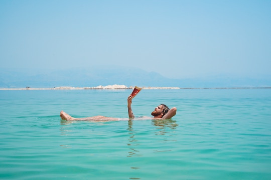 Image of a man floating in water and reading a book