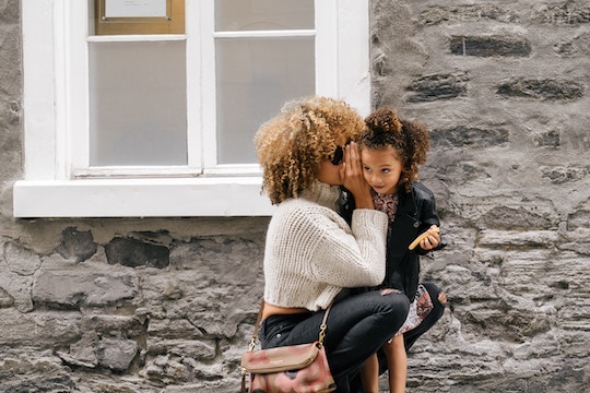 Image of a woman whispering to a child